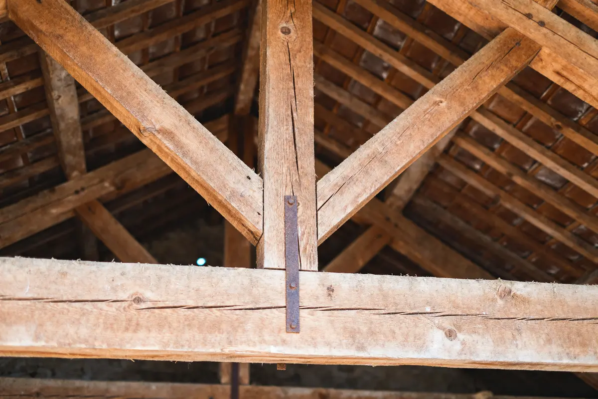 Structure de charpente en bois avec chevêtrement visible dans un toit de bâtiment ancien